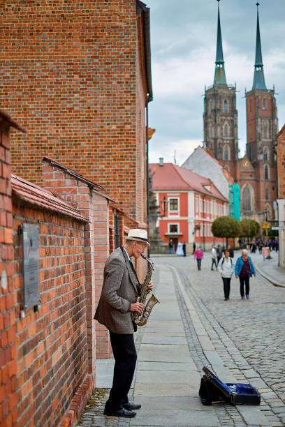 street musician with saxophone on pedestrian tumski bridge with cathedral of st. john the baptist on the background. wroclaw, poland. - medieval autumn cathedral vertical imagens e fotografias de stock