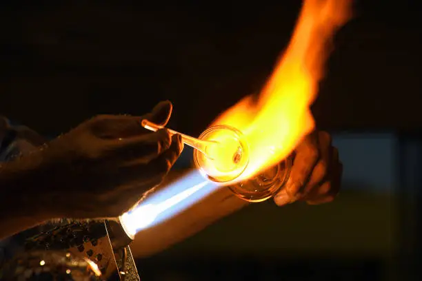 close up of glass blower using glassblowing torch