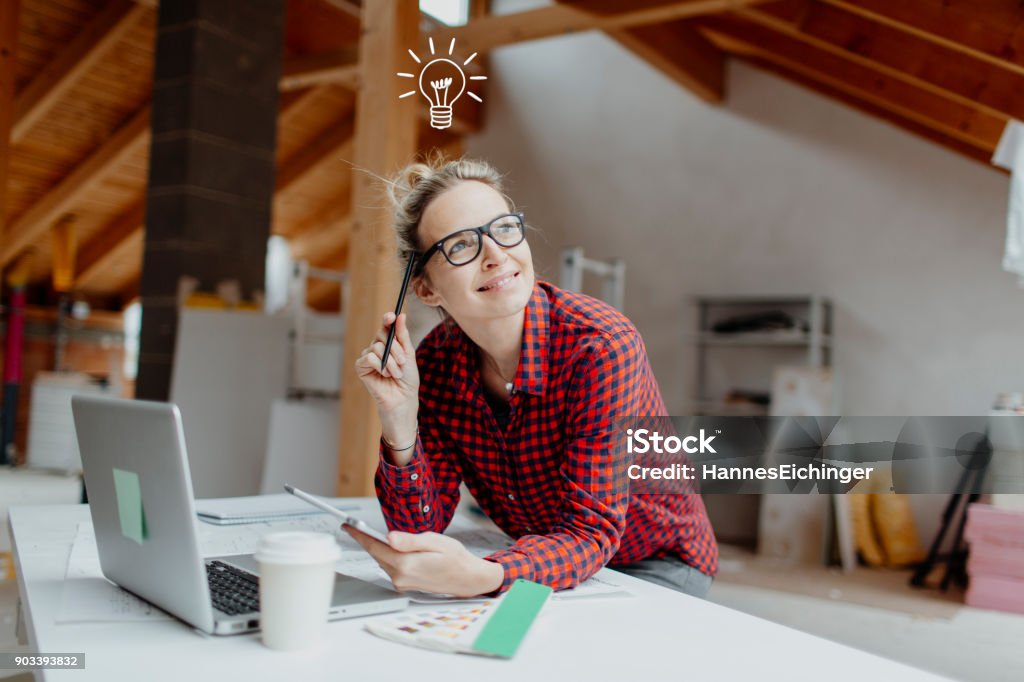 young, pretty, blonde woman is planning on the notebook and tablet the expansion of her loft and a light goes on her beautiful young, pretty, blonde woman is planning on the notebook and tablet the expansion of her loft and a light goes on her Renovation Stock Photo