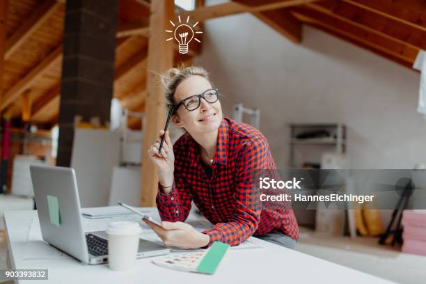 Young Pretty Blonde Woman Is Planning On The Notebook And Tablet The Expansion Of Her Loft And A Light Goes On Her Stock Photo - Download Image Now