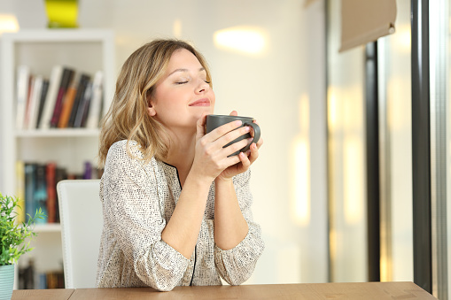 istock Mujer sosteniendo una taza de café en casa de respiración 903397254
