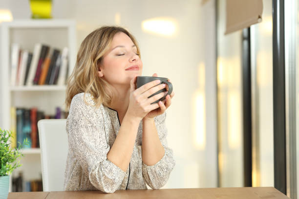 mujer sosteniendo una taza de café en casa de respiración - café bebida fotos fotografías e imágenes de stock