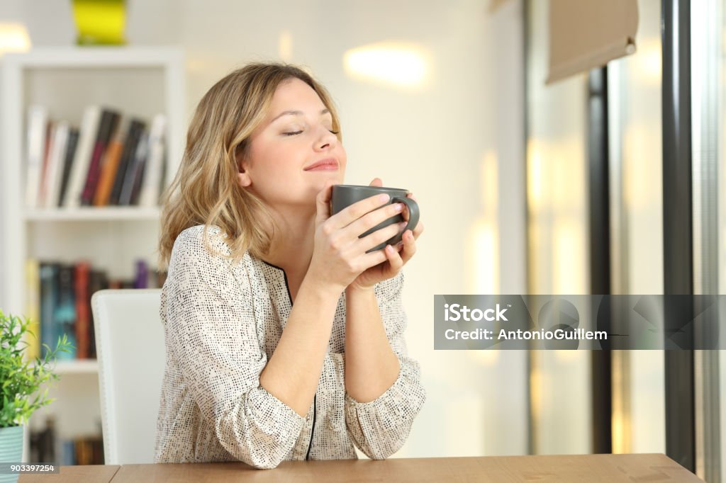 Woman breathing holding a coffee mug at home Portrait of a woman breathing and holding a coffee mug at home Coffee - Drink Stock Photo