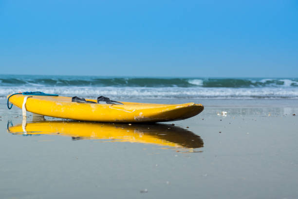 A yellow surfboard lays on Kotu Beach in The Gambia, West Africa