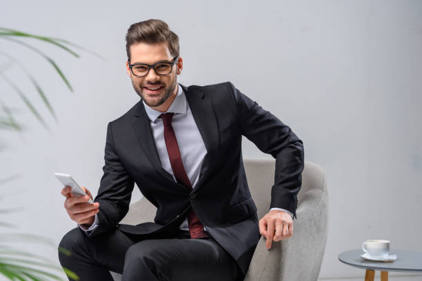 istock smiling businessman holding smartphone and looking at camera 903409250