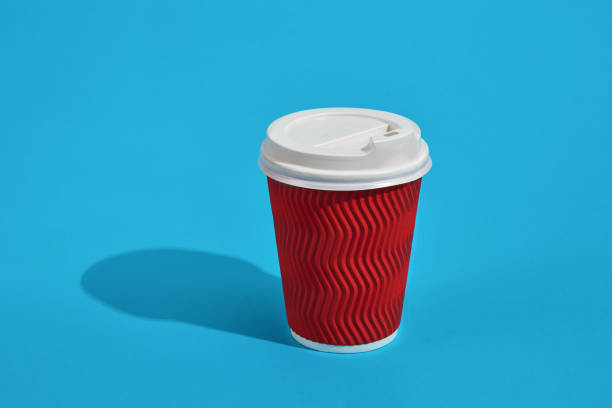 istock Hot coffee in red paper cup with white lid on blue background wi 903409530