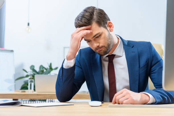 istock confused businessman sitting at working table and looking down 903410272