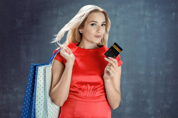 Elegant young woman with shopping bags holds loyalty card in hand stock photo