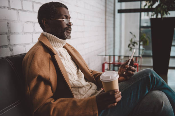istock man holding coffee and looking at smartphone 903416226