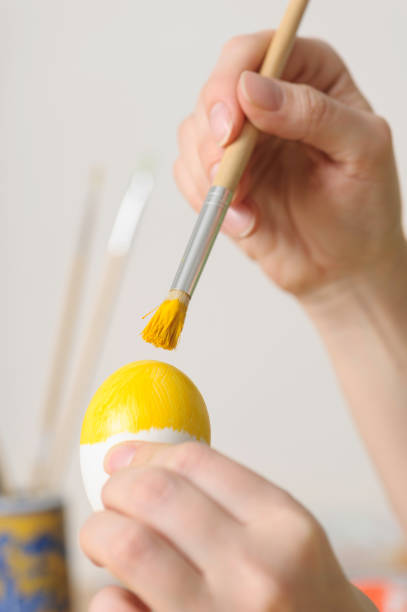 Close up of woman hands coloring easter egg