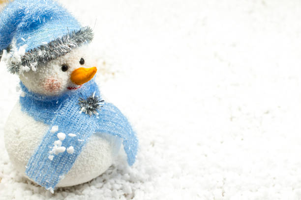 istock Snowman in a blue hat and a gift in a red box on the snow 903428760
