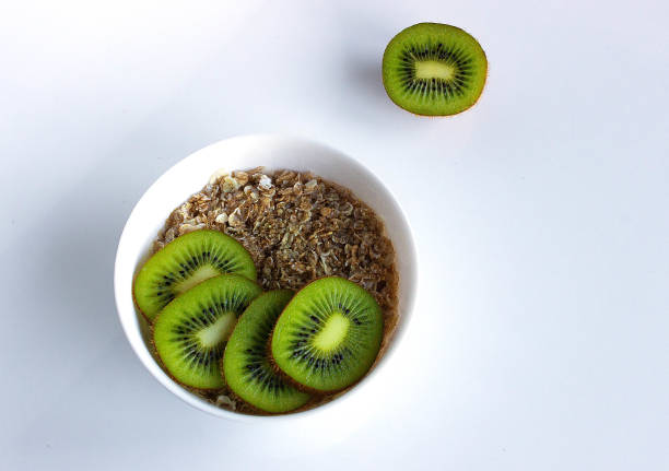 Healthy breakfast: oatmeal with kiwi on white plate on white background