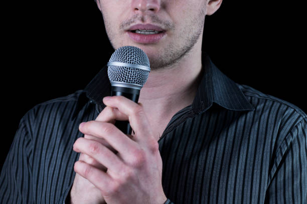 istock Front view of a man speaking to microphone on black background. 903449420