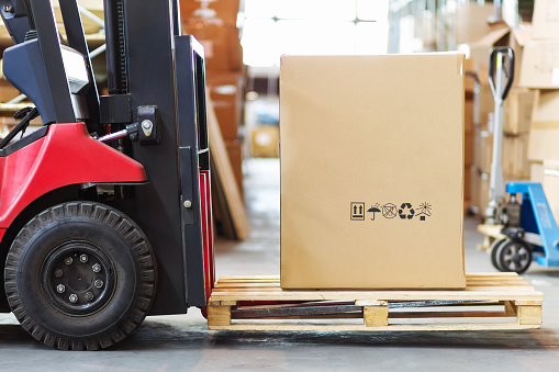 a large photograph of the part of the forklift in the form of a wheel and forks on which you lay a pallet with a large cortone box.
