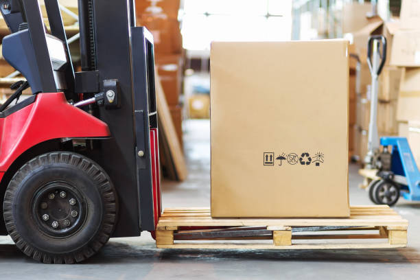 part of a forklift in the form of a wheel and a pitchfork with a large cortone box - warehouse forklift distribution warehouse merchandise imagens e fotografias de stock