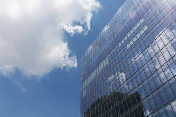 istock Bottom view of modern, glass building (skyscraper). Clouds and their reflections on glass surface create dramatic atmosphere. 903449952