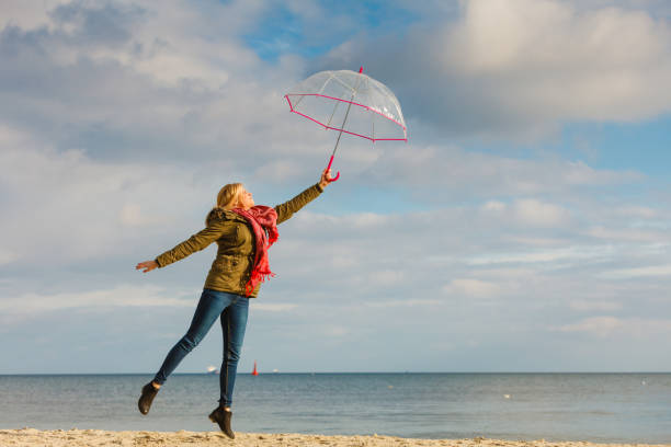 istock Woman jumping with transparent umbrella on beach 903450378