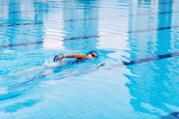 Female swimmer on evening training on swimming pool, warming up, swimming freestyle and butterfly during training. She is determined to win