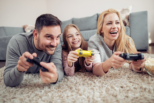 Competitive young family playing video games in a living room.