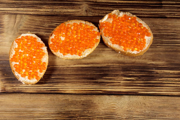 sandes com manteiga e caviar vermelho na mesa de madeira - plank bread caviar close up - fotografias e filmes do acervo