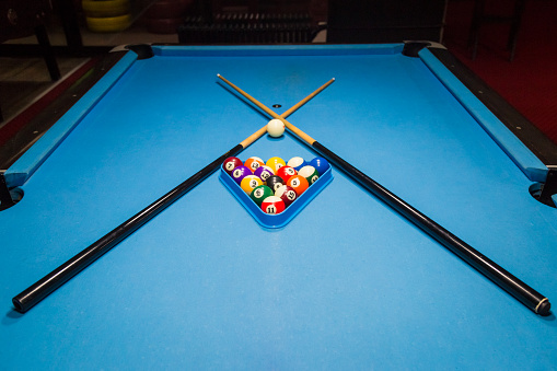 Billiards balls and cue on billiards table