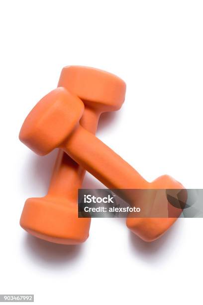 Two Orange Dumbbells Lie On Top Of Each Other On A White Background Stock Photo - Download Image Now