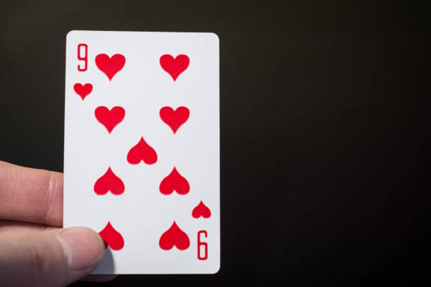 istock Abstract: man hand holding playing card nine of hearts on a black background with copyspace 903483246