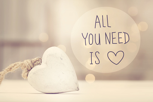 All You Need Is Love message with a white heart  in a room
