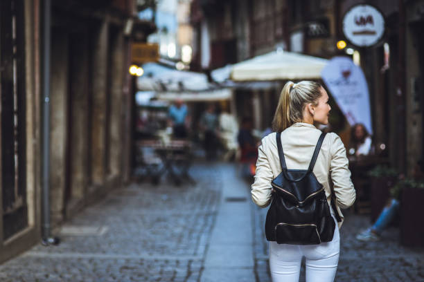 istock Young woman with backpack walking on the european streets 903490590