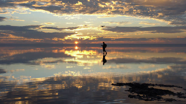 Travelist having fun with Drone on salt lake at sunset