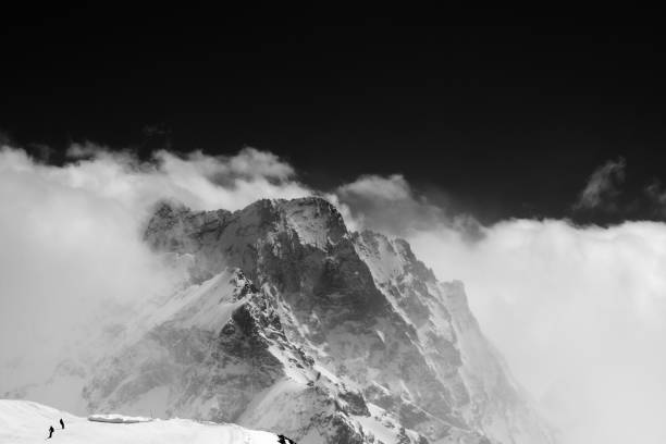 istock Black and white view on snow mountains in clouds 903495410