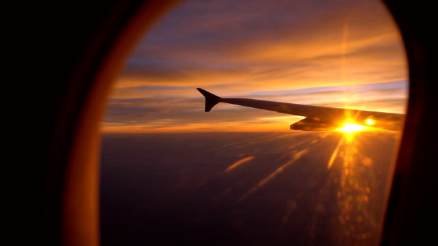 Sunset Flight with aircraft wing from an airplane window