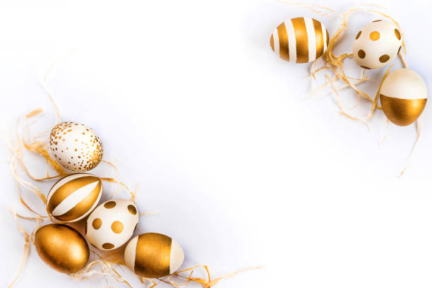 Top view of easter eggs colored with golden paint in differen patterns. Various striped and dotted designs. White background. Copy space.