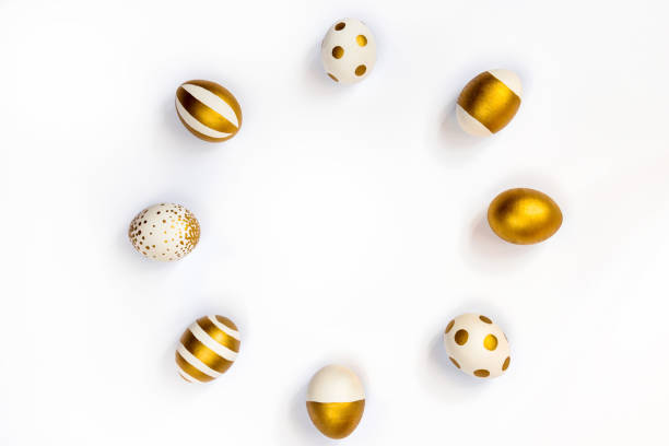 istock Top view of easter eggs colored with golden paint in differen patterns arranged in circle. Various striped and dotted designs. White background. Copy space. 903527312
