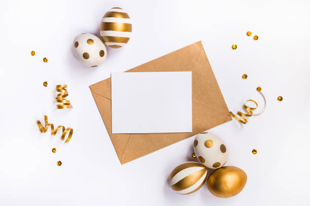 istock Easter festive decoration. Top view of easter eggs colored with golden paint in differen patterns and empty mock-up card in a kraft envelope. Various striped and dotted designs. White background. 903527436