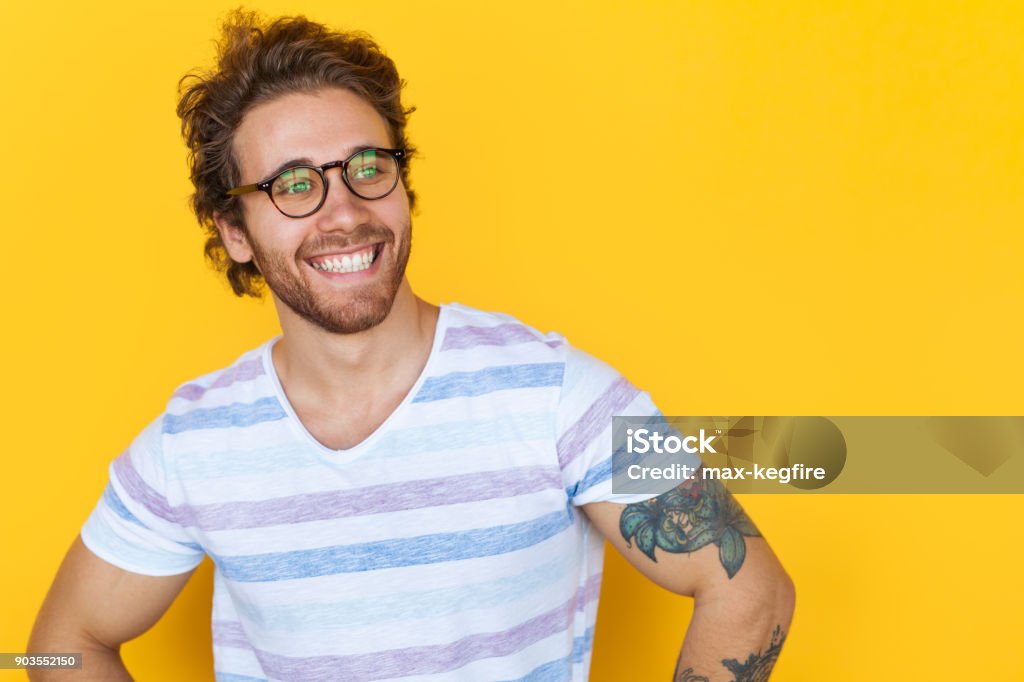 Souriant bel homme posant sur jaune - Photo de Hommes libre de droits