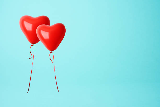 istock Two red heart shape balloons against blue background 903553038