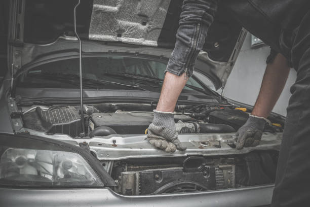 istock Car mechanic looking to the engine in the garage. Car motor repair. Problems and solutions concept. 903556004