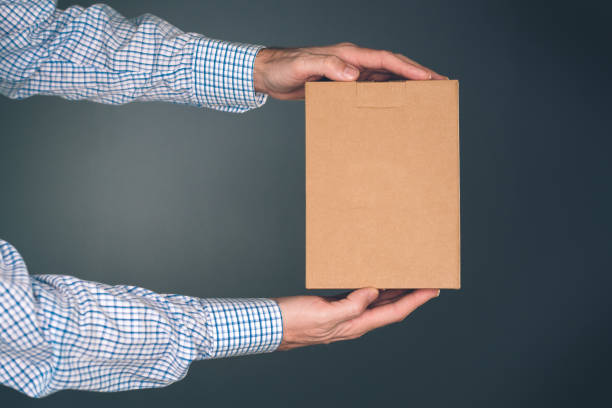 istock Man holding cardboard box package for mock up design 903557420