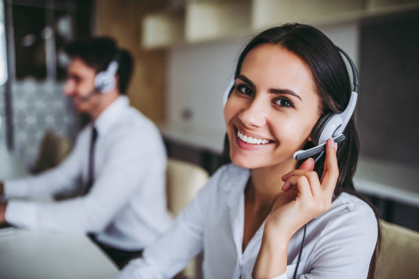 Call center workers. How can I help you? Beautiful call center workers in headphones are working at modern office. telephone worker stock pictures, royalty-free photos & images