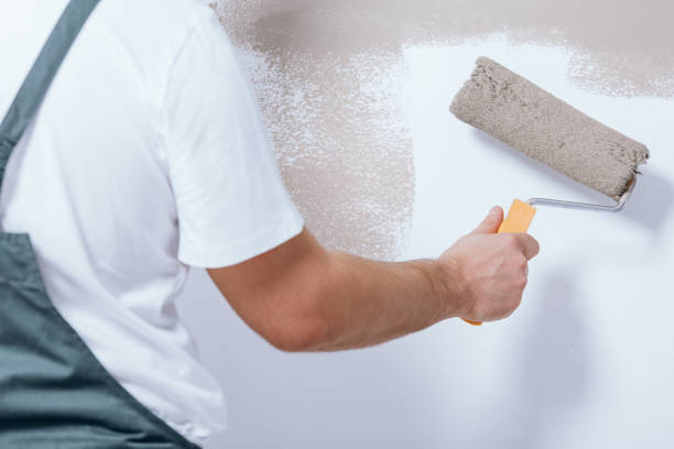 Close-up of handyman holding roller Close-up of handyman holding roller and painting white wall house painter stock pictures, royalty-free photos & images
