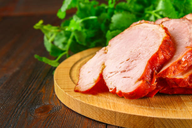 istock Sliced Roast Pork Loin on a brown wooden table with cilantro. 903577596