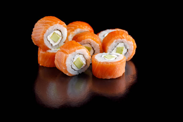 Original set of sushi with salmon, avocado and Philadelphia cheese on a black background close-up. stock photo