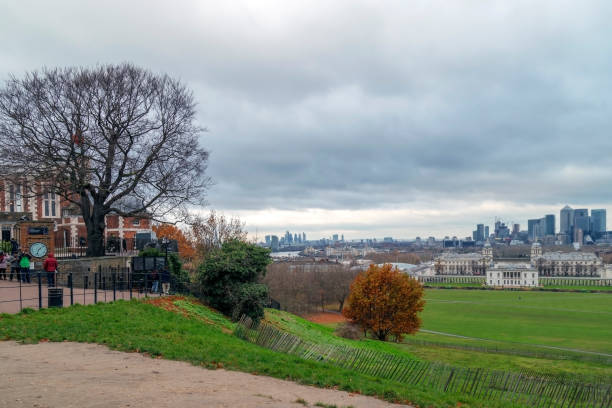 People that visit Royal Greenwich Observatory, skyline of Canary Wharf and Queen's House London: Panoramic view with people that visit Royal Greenwich Observatory at Greenwich Hill, skyline of Canary Wharf and Queen's House. queen's house stock pictures, royalty-free photos & images