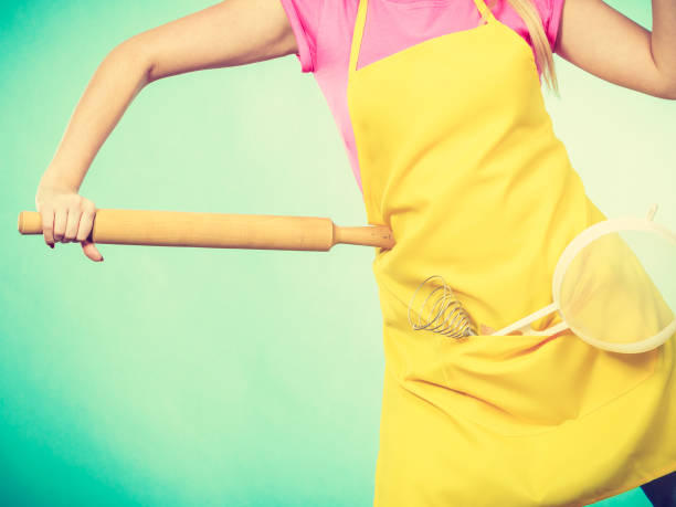 istock Woman wearing apron holding colander and rolling pin 903593440