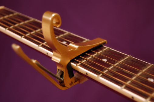 CLOSE UP OF A MALE HAND TUNING GUITAR PEGS ON HEADSTOCK.