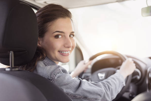 giovane donna alla guida della sua auto - driving women rear view sitting foto e immagini stock