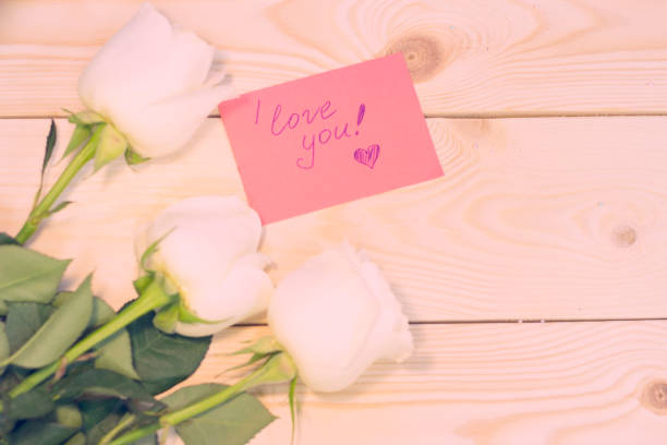 istock White roses on natural wooden background 903596520