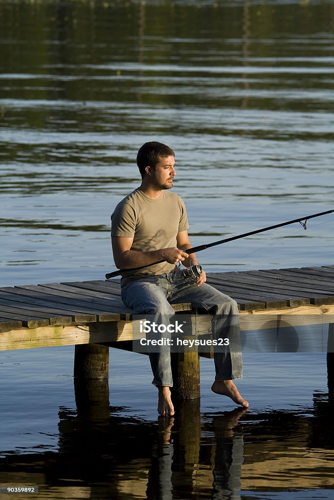 Jeune homme pêche sur un ponton - Photo de Activité de loisirs libre de droits