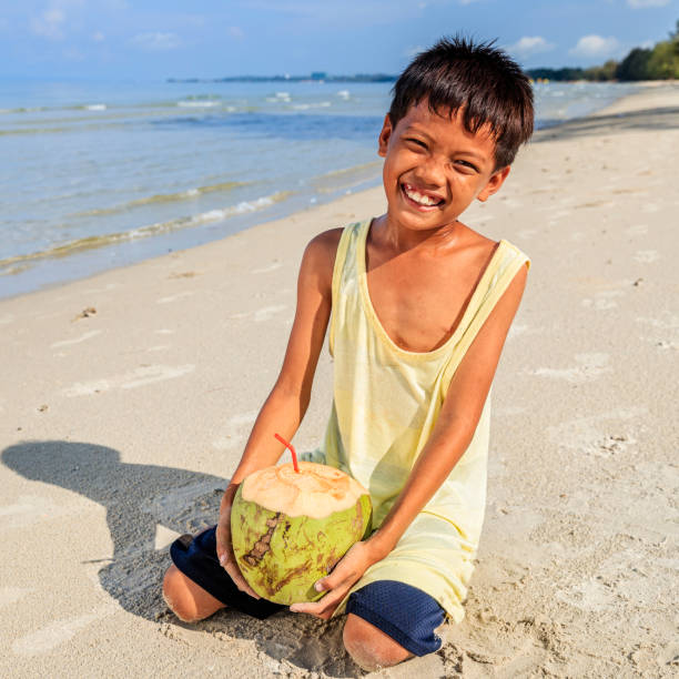 istock Cambodian young boy holding coconut on the beach, Cambodia 903600846